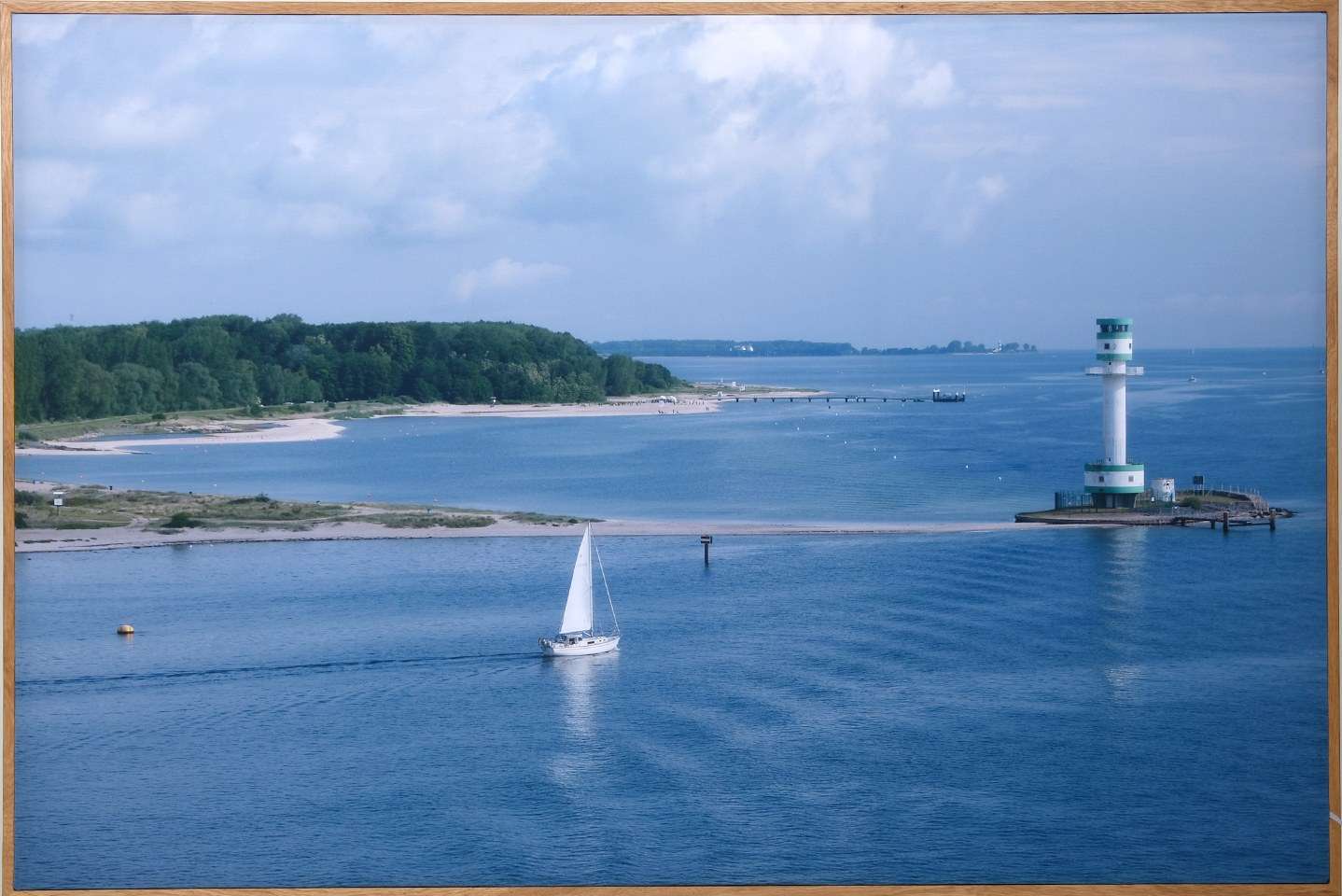 Akustikbild im Eichenrahmen, frontal, Motiv: Leuchtturm und Segelboot vor bewaldetem Ufer.